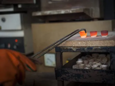 Glowing cupels resting on the bench after leaving the furnace
