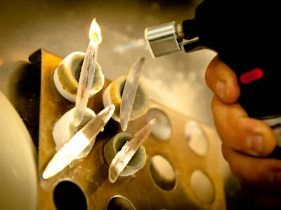 Fire-assay buttons being torched free of their cupels