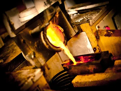 Close-up of molten gold pouring from the furnace into a mould