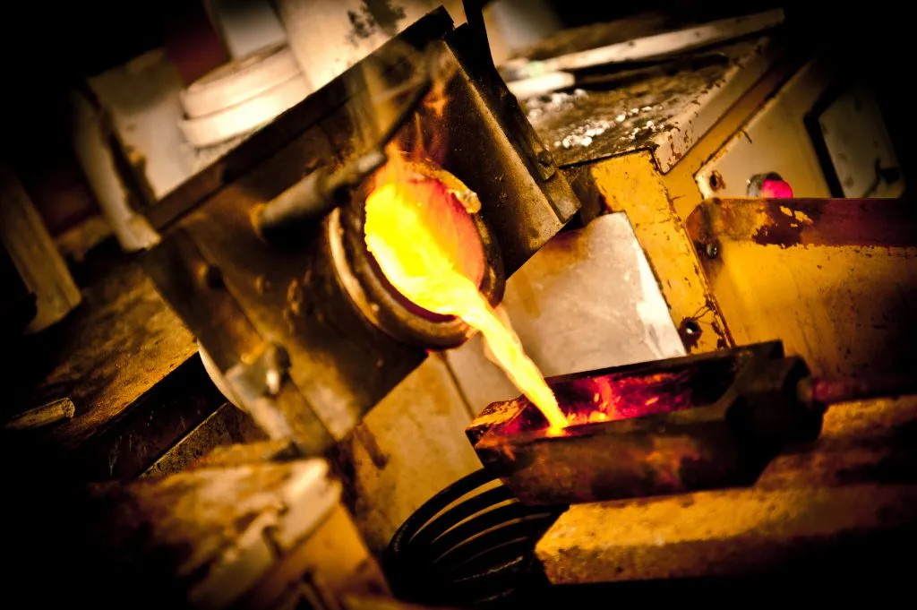 Molten gold pouring from the crucible into an ingot mould on the refinery floor