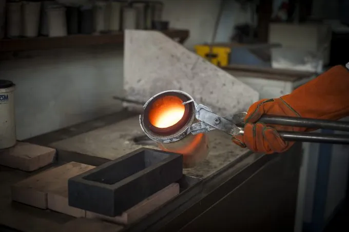 Molten gold being poured from a crucible into an ingot mould