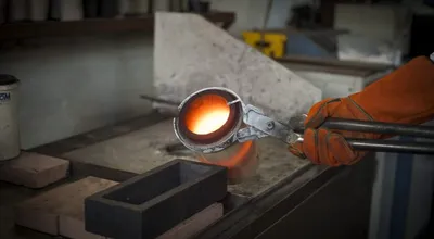 Molten gold being poured from a crucible into an ingot mould