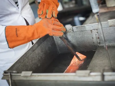 A gold bar being quenched in a water tank